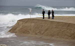 People watch as the Carmel River flows to the ocean at Carmel River State Beach on Monday, January 11, 2016.  County crews worked with equipment on Sunday to start the breach through the sand bar at the southern channel.  The river broke through on its own sometime Sunday night.  (Vern Fisher - Monterey Herald)